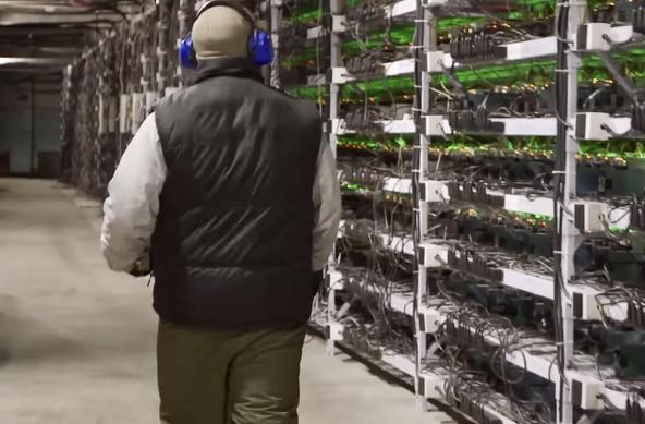 A worker in a data center surrounded by racks of computer chips.